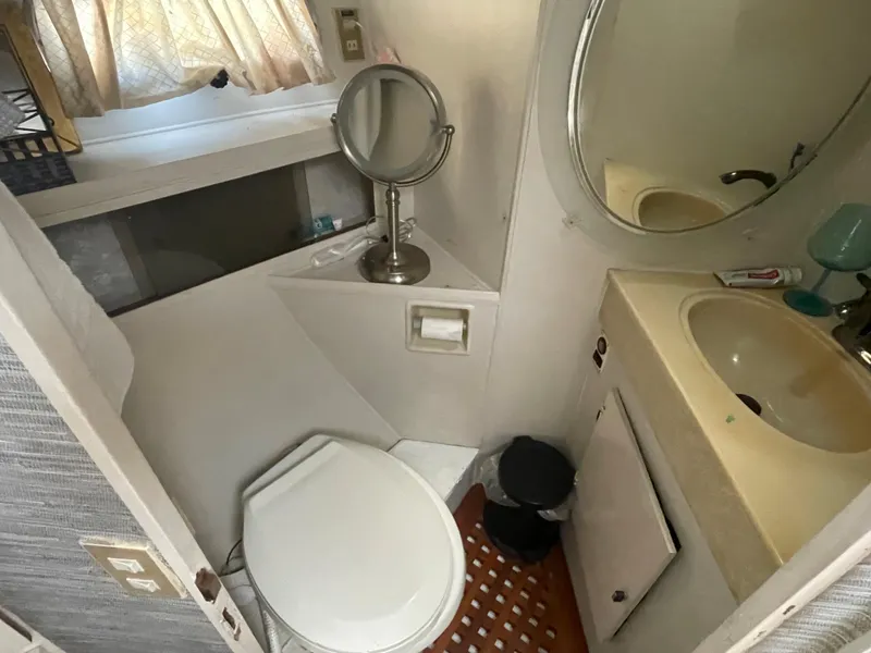 Slide: The Image of Compact bathroom in a 1986 Sea Hawk Sedan, featuring a toilet, sink, and mirror. - 26