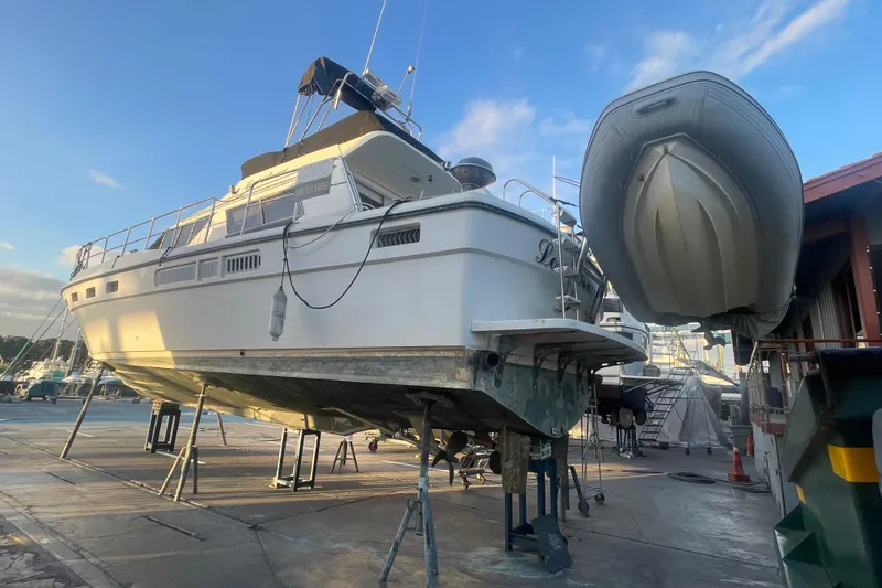 Slide: The Image of 1986 Sea Hawk Sedan boat on dry dock with inflatable dinghy, under clear blue sky. - 56