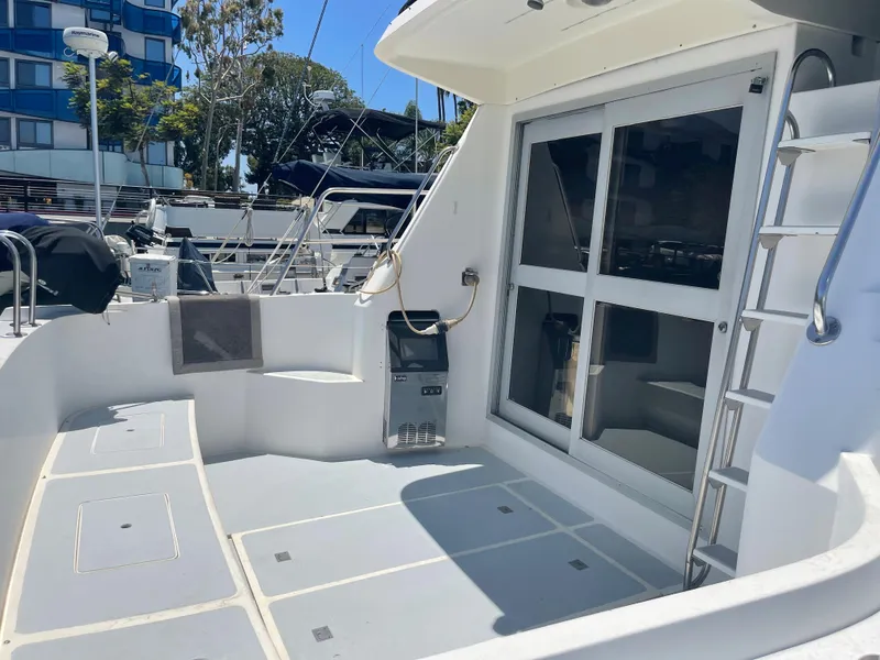 Slide: The Image of 1986 Sea Hawk Sedan boat deck with seating, ladder, and marina view. - 6