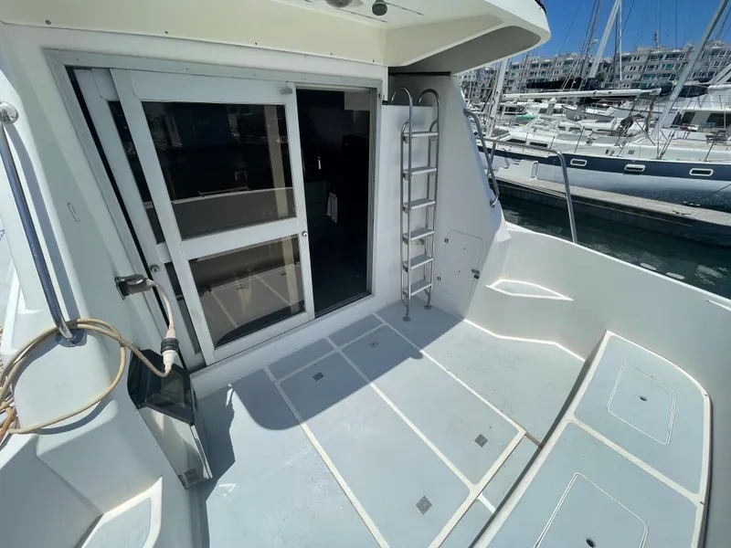 Slide: The Image of 1986 Sea Hawk Sedan boat deck with sliding door and ladder, docked at marina. - 7