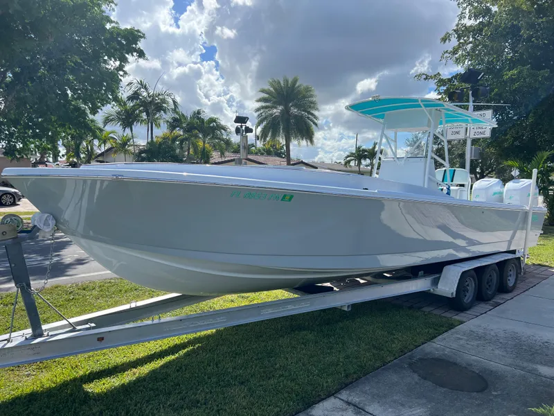 Slide: The Image of 1987 Intrepid 300 Center Console boat on a trailer, parked outdoors with palm trees in the background. - 1