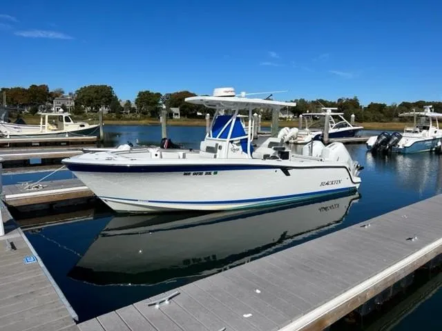 Slide: The Image of 2019 Blackfin 242 CC boat docked at a marina on a sunny day. - 2