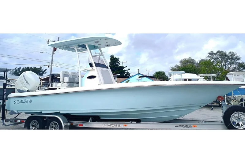Slide: The Image of 2023 ShearWater 260 SS boat on trailer, light blue hull, outdoor setting. - 2