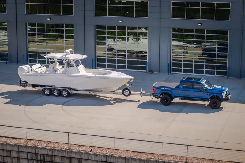 Slide: The Image of 2023 Fountain 34 Tournament Edition boat on trailer, towed by blue truck. - 32