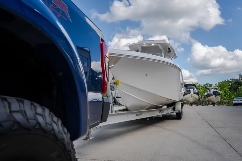 Slide: The Image of 2023 Fountain 34 Tournament Edition boat on trailer, parked beside a blue truck under a cloudy sky. - 17