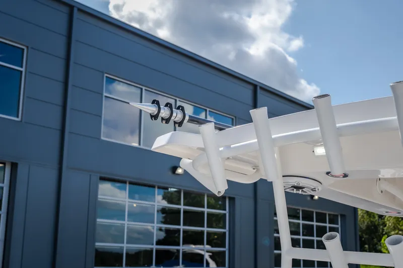 Slide: The Image of 2023 Fountain 34 Tournament Edition boat detail with rod holders, against a modern building backdrop. - 80