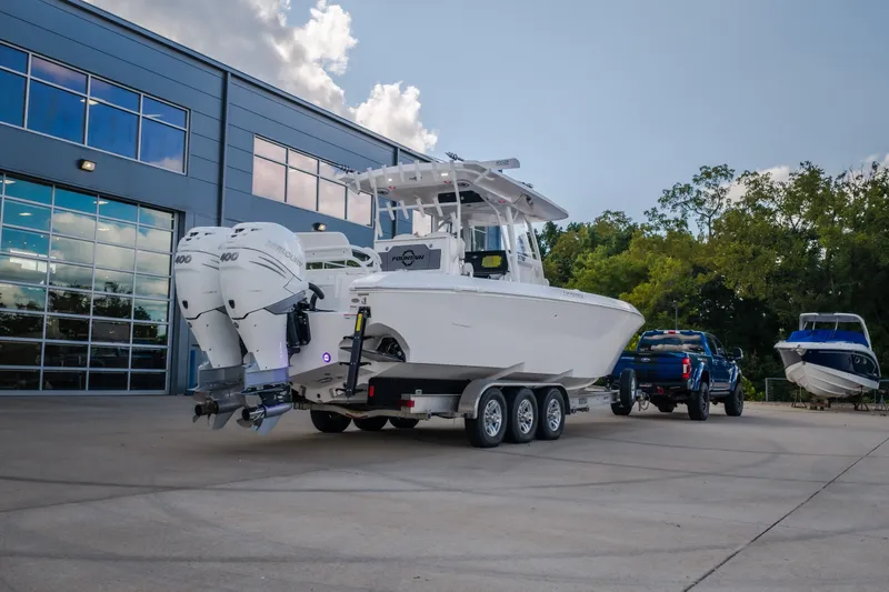 Slide: The Image of 2023 Fountain 34 Tournament Edition boat on trailer, parked near a modern building. - 18