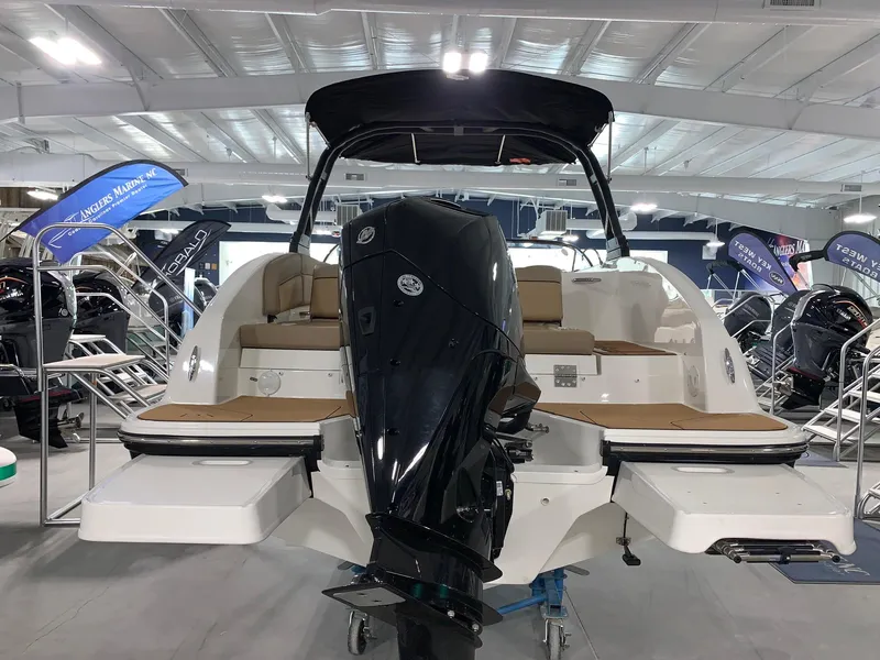 Slide: The Image of 2024 Bayliner DX2200 boat displayed in a showroom with a powerful outboard motor. - 3