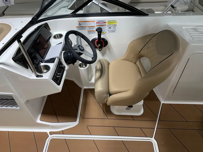 Slide: The Image of 2024 Bayliner DX2200 boat helm with tan captain's chair and modern dashboard. - 9