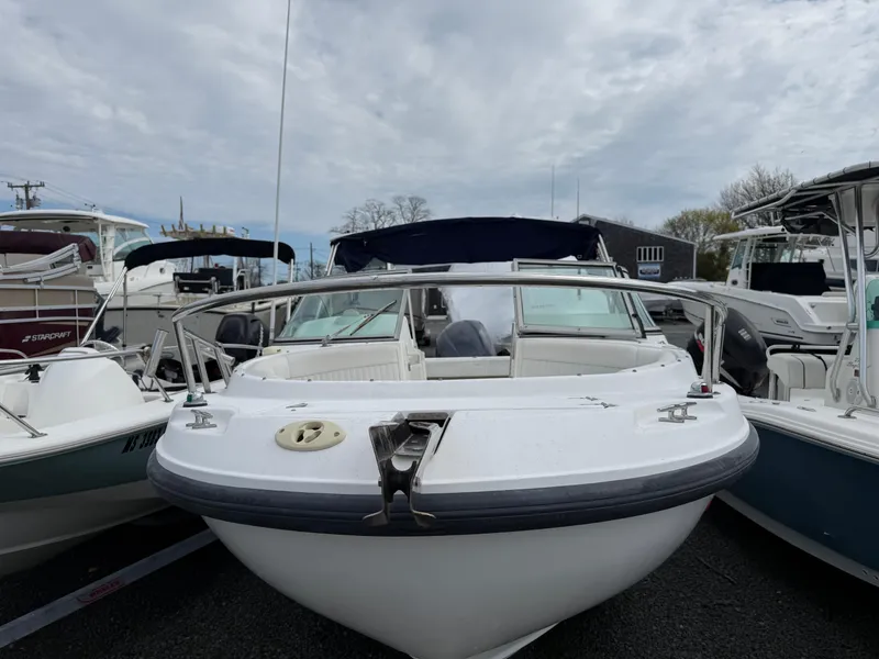 Slide: The Image of 2002 Boston Whaler VENTURA 210 boat docked among other vessels under cloudy skies. - 2