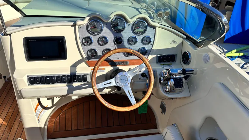 Slide: The Image of 2014 Chris-Craft 28 LAUNCH boat dashboard with wooden steering wheel and modern controls. - 5