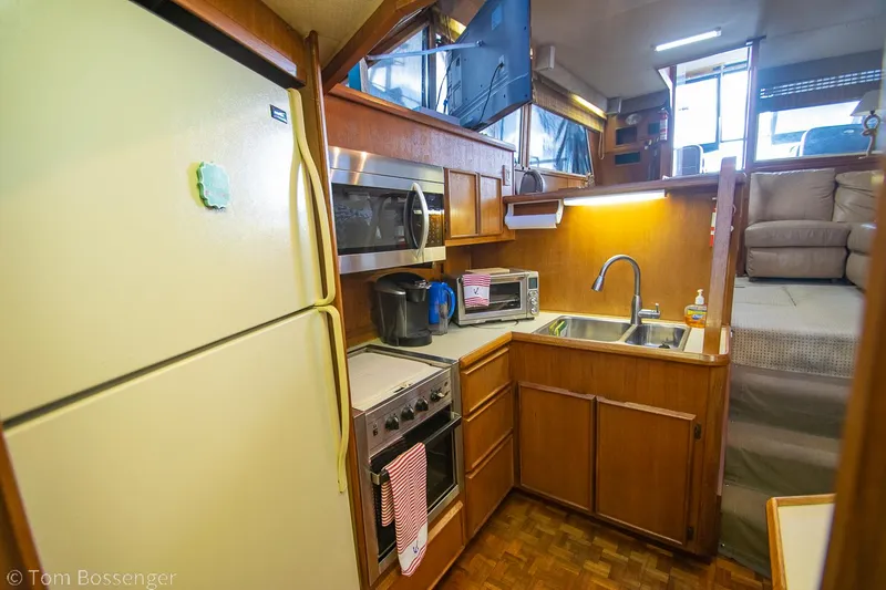 Slide: The Image of 1986 Chris-Craft Corinthian kitchen with appliances, wooden cabinetry, and cozy seating area. - 13