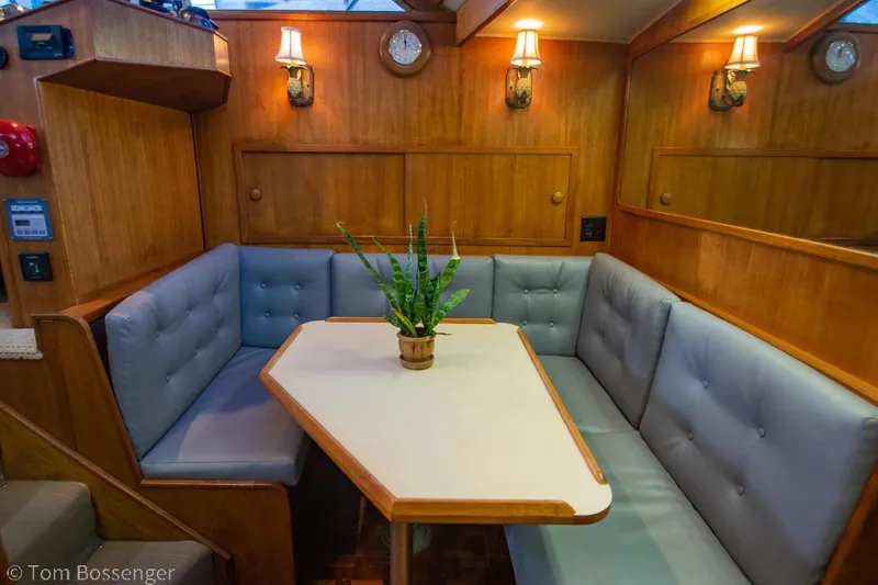 Slide: The Image of 1986 Chris-Craft Corinthian interior with cozy dining area, wooden paneling, and soft lighting. - 15