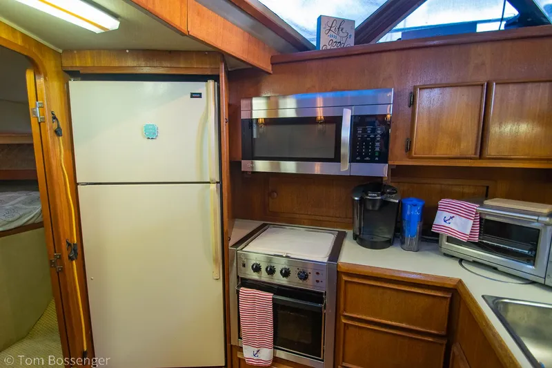 Slide: The Image of 1986 Chris-Craft Corinthian kitchen with fridge, microwave, and stove in wooden cabinetry. - 16