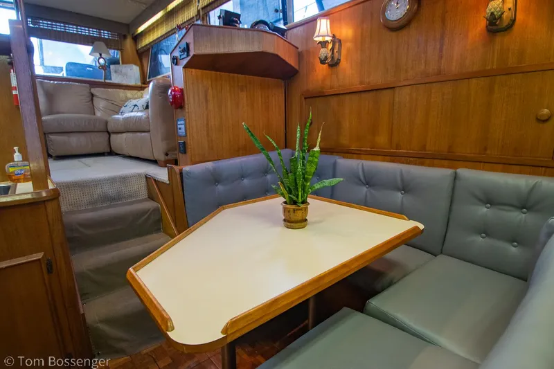 Slide: The Image of 1986 Chris-Craft Corinthian interior with cozy seating, table, and plant decor. - 19