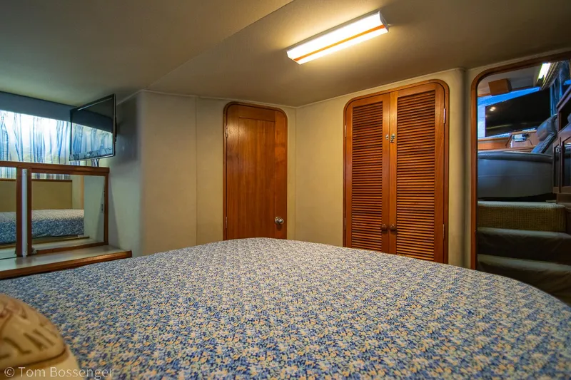 Slide: The Image of 1986 Chris-Craft Corinthian cabin interior with bed, wooden doors, and soft lighting. - 24