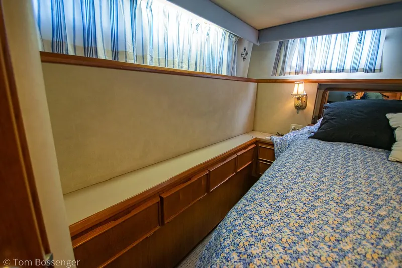Slide: The Image of 1986 Chris-Craft Corinthian cabin interior with bed, wooden cabinets, and striped curtains. - 25