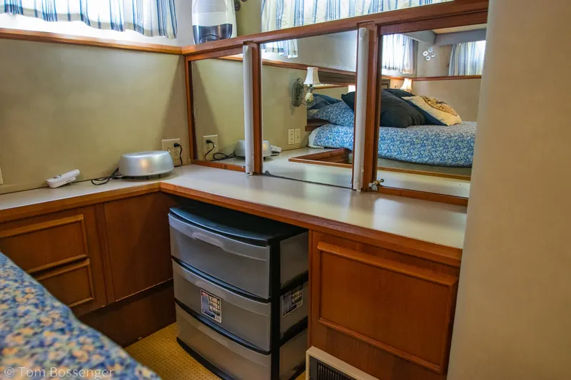 Slide: The Image of 1986 Chris-Craft Corinthian cabin interior with mirrors, storage drawers, and cozy bedding. - 26