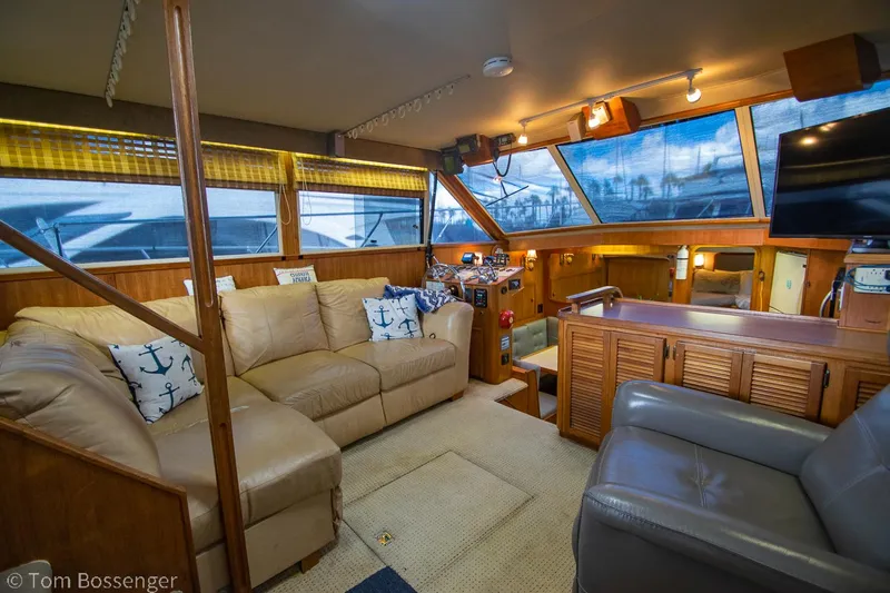 Slide: The Image of 1986 Chris-Craft Corinthian yacht interior with beige seating, nautical decor, and large windows. - 7