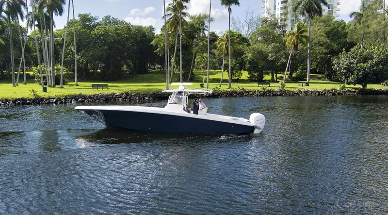 Slide: The Image of 2016 Fountain 38 CC Tournament Edition boat cruising on a scenic lake with lush greenery. - 10