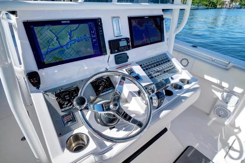 Slide: The Image of 2016 Fountain 38 CC Tournament Edition boat dashboard with dual navigation screens and steering wheel. - 19