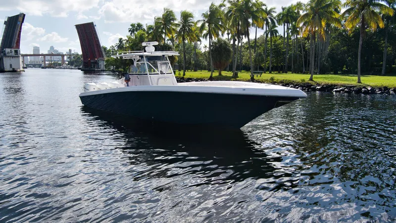 Slide: The Image of 2016 Fountain 38 CC Tournament Edition boat cruising near a drawbridge and palm trees. - 2