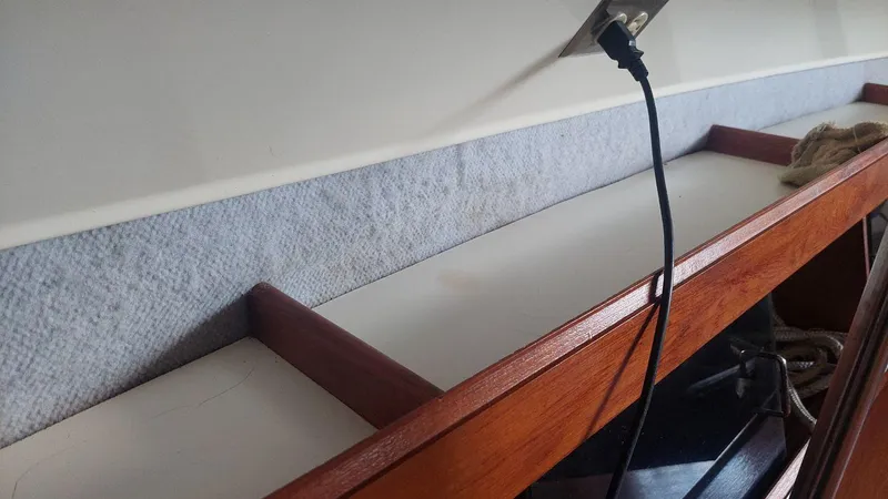 Slide: The Image of Interior shelf of 1987 Hunter 34 sailboat with wooden trim and electrical outlet. - 18