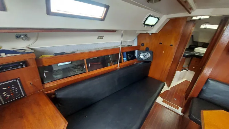 Slide: The Image of Interior of a 1987 Hunter 34 sailboat, featuring wooden cabinetry and black seating. - 20