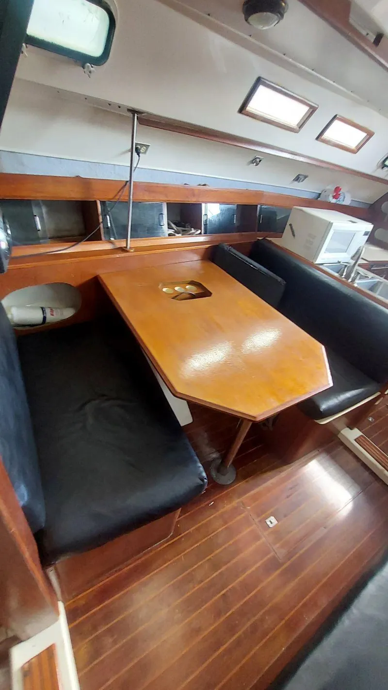 Slide: The Image of 1987 Hunter 34 sailboat interior with wooden table and seating area. - 27
