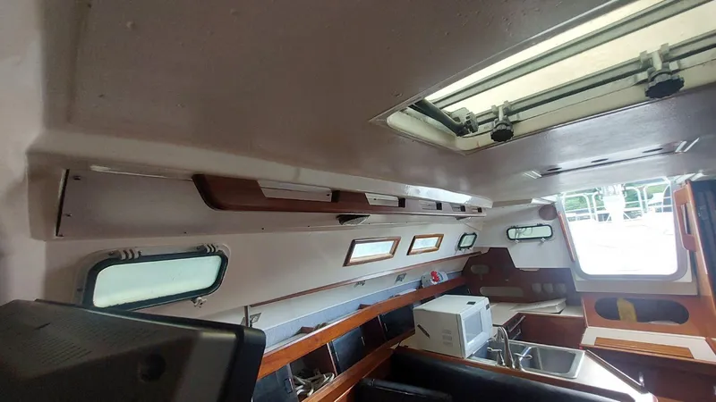 Slide: The Image of Interior of 1987 Hunter 34 sailboat with wooden cabinetry and multiple windows. - 29