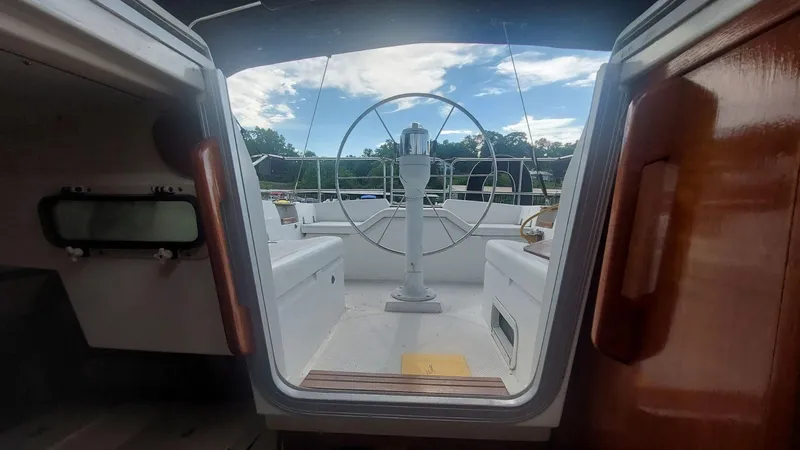 Slide: The Image of 1987 Hunter 34 sailboat cockpit view with steering wheel, under a partly cloudy sky. - 34