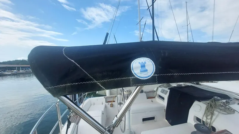 Slide: The Image of 1987 Hunter 34 sailboat with black sail cover docked at marina. - 38