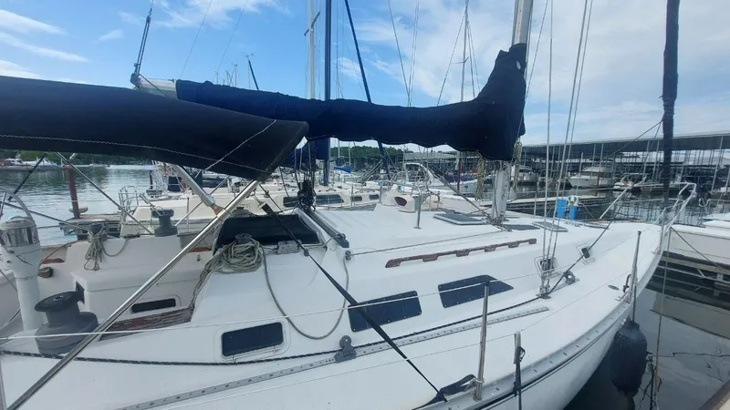 Slide: The Image of 1987 Hunter 34 sailboat docked at marina, featuring white deck and black sails. - 39