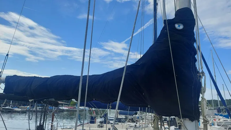 Slide: The Image of 1987 Hunter 34 sailboat with covered boom, docked at marina under blue sky. - 4