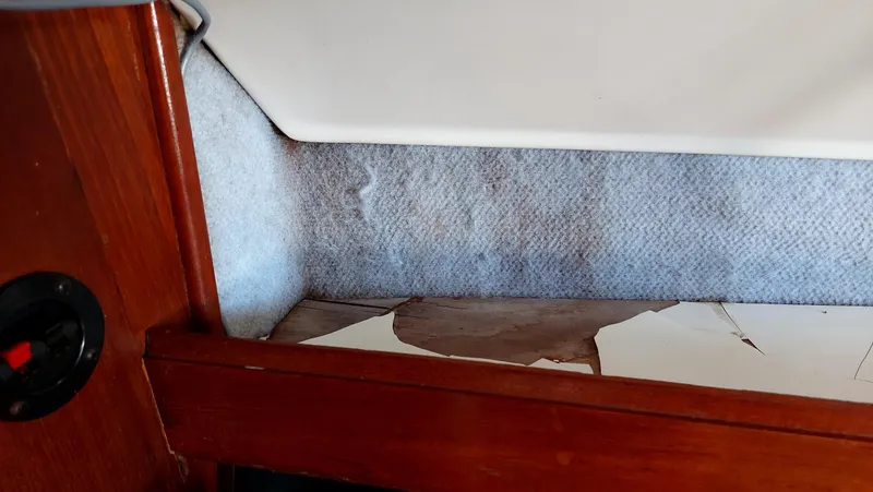 Slide: The Image of Interior damage on 1987 Hunter 34 sailboat, showing peeling wood and worn fabric. - 46
