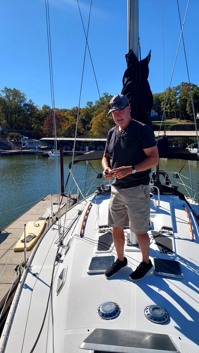 Slide: The Image of Man standing on 1987 Hunter 34 sailboat docked at marina. - 49