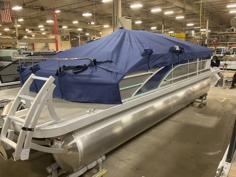 Slide: The Image of 2023 Bennington 22 LSB pontoon boat with blue cover in a warehouse. - 2