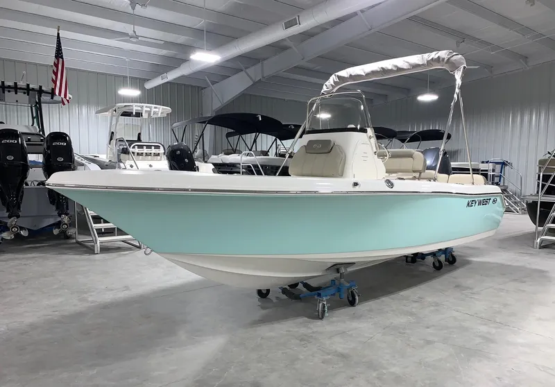 Slide: The Image of 2024 Key West 189 FS boat in showroom, light blue hull, white interior, canopy. - 0