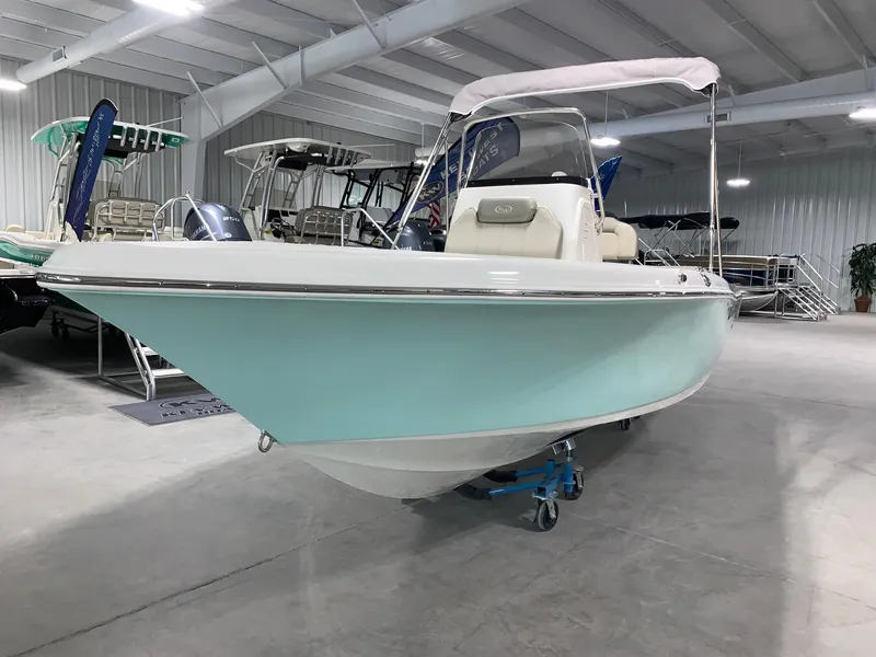 Slide: The Image of 2024 Key West 189 FS boat in showroom, light blue hull, white interior, and canopy. - 1