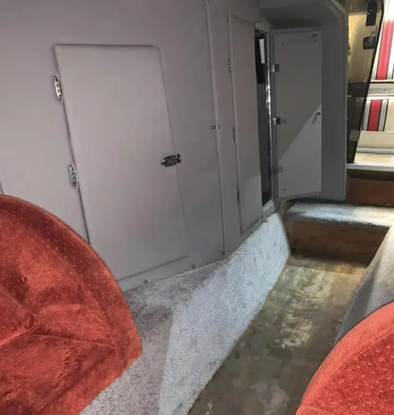 Slide: The Image of Interior of a 1989 Fountain 12m boat with red seats and carpeted flooring. - 13