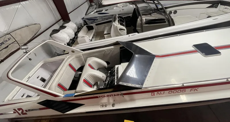 Slide: The Image of 1989 Fountain 12m speedboat with white and red interior, docked in a storage facility. - 6