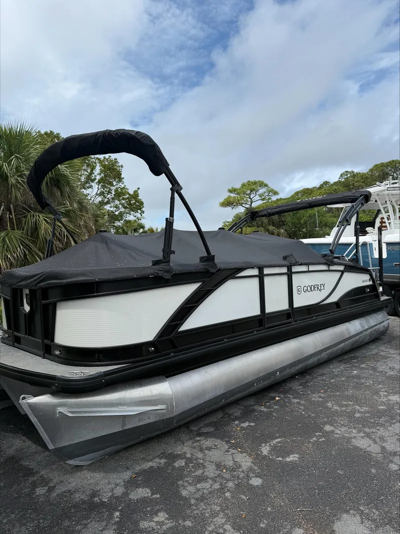 Slide: The Image of 2023 MONACO 235 DFL pontoon boat with cover, parked outdoors. - 2