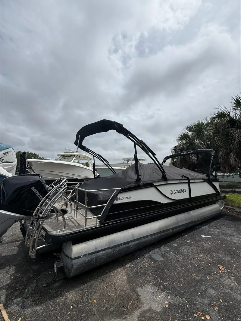 Slide: The Image of 2023 MONACO 235 DFL pontoon boat parked outdoors under cloudy sky. - 4