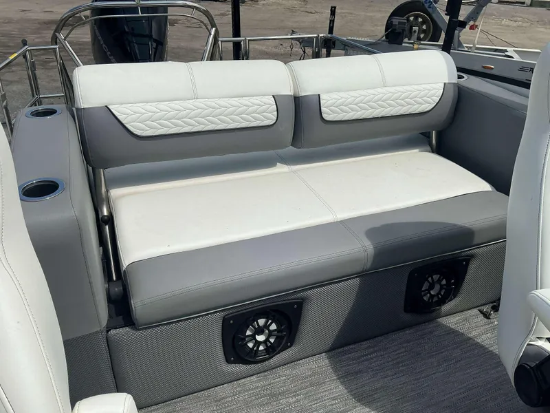 Slide: The Image of 2023 MONACO 235 DFL boat seating with white and gray upholstery, cup holders, and speakers. - 5