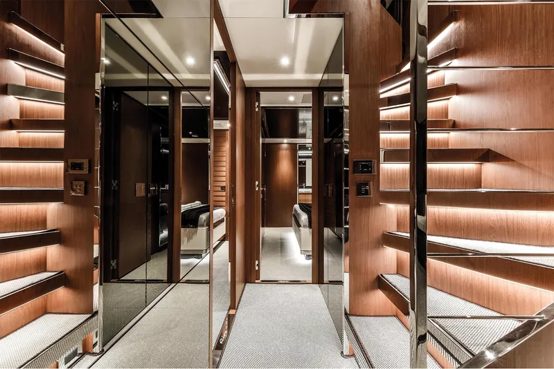 Slide: The Image of Luxurious interior of 2024 Riva 90' Argo yacht with modern wooden staircase and mirrored walls. - 18