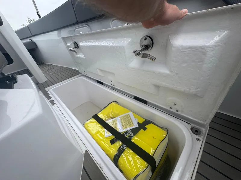 Slide: The Image of Open storage compartment on 2023 Iguana Sport boat with yellow safety equipment inside. - 19
