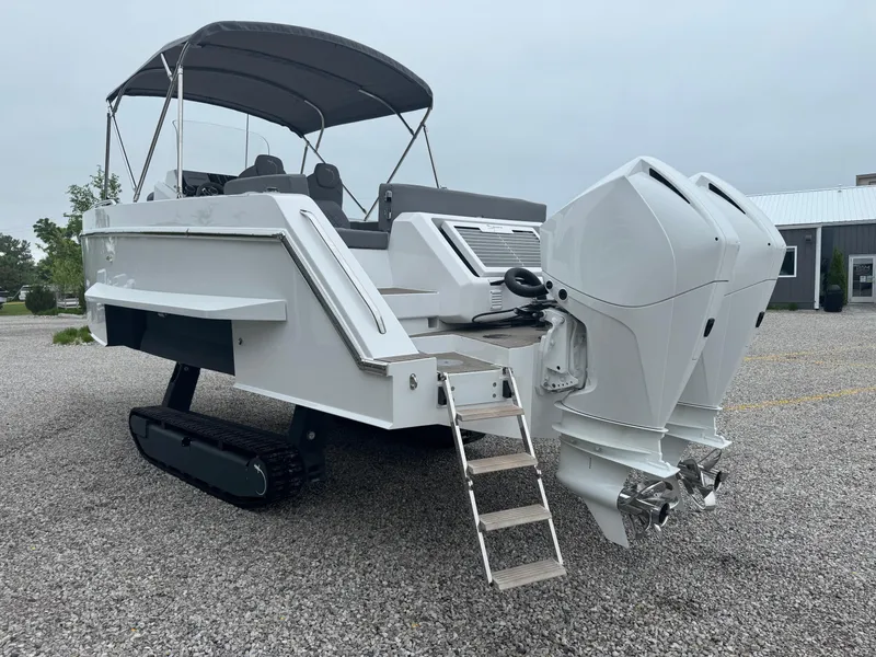 Slide: The Image of 2023 Iguana Sport boat with dual outboard motors and retractable tracks on gravel surface. - 5
