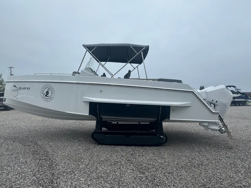 Slide: The Image of 2023 Iguana Sport boat with canopy and tracks, parked on gravel. - 6