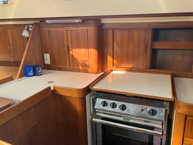Slide: The Image of 1989 Pearson 39-2 yacht interior kitchen with wooden cabinets and stainless steel stove. - 25
