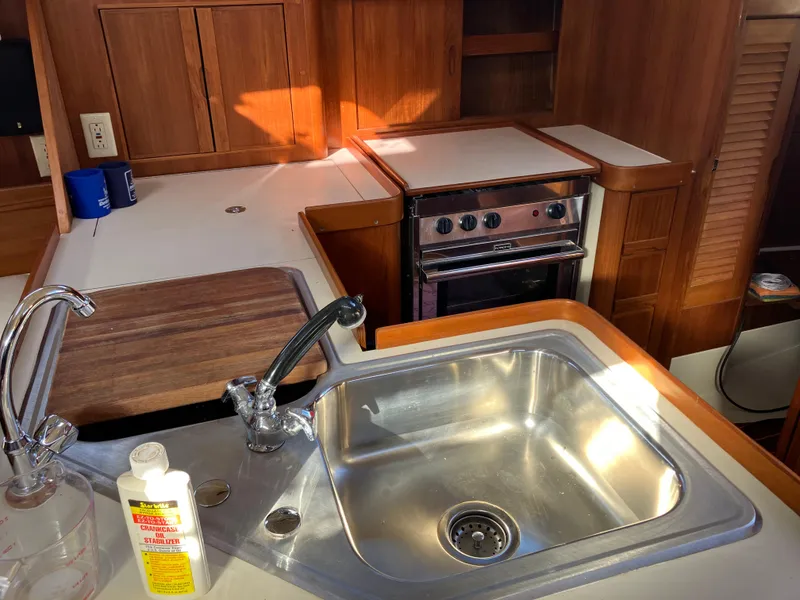 Slide: The Image of Galley kitchen in 1989 Pearson 39-2 sailboat with sink, stove, and wooden cabinetry. - 26